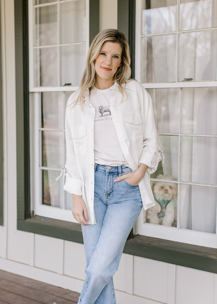 Model wearing jeans, tee and cream button up top with patch pockets and long sleeves.