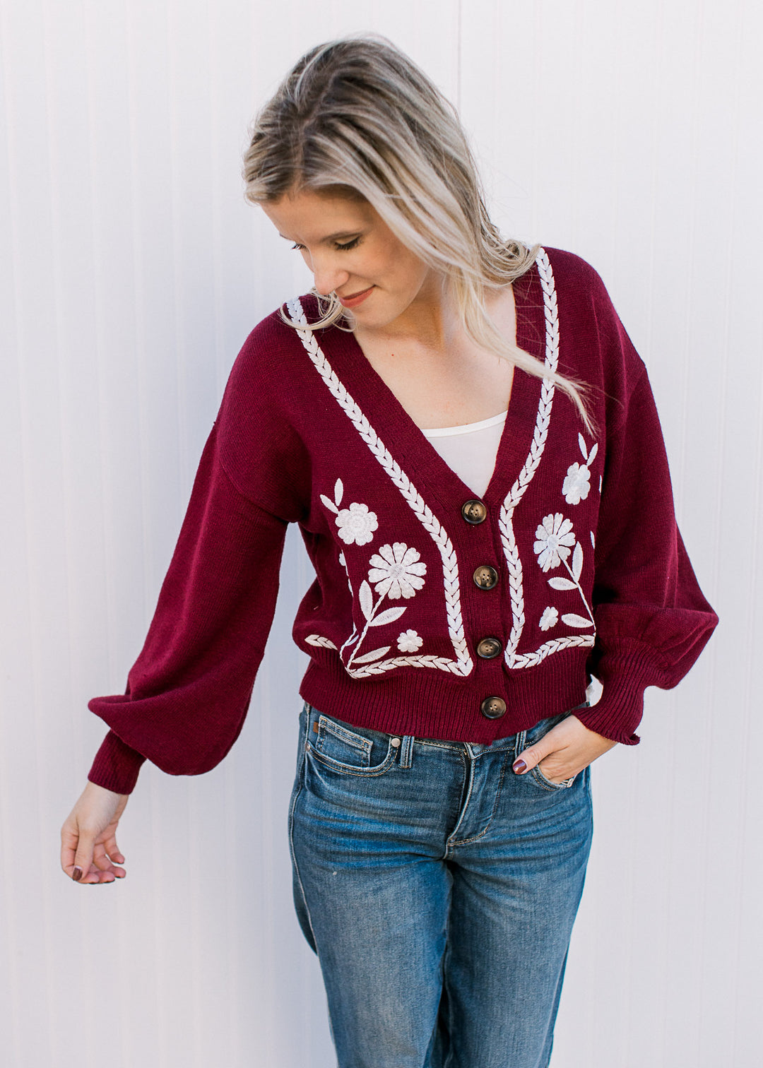 Model wearing a wine sweater with white embroidery, button front and bubble long sleeves.