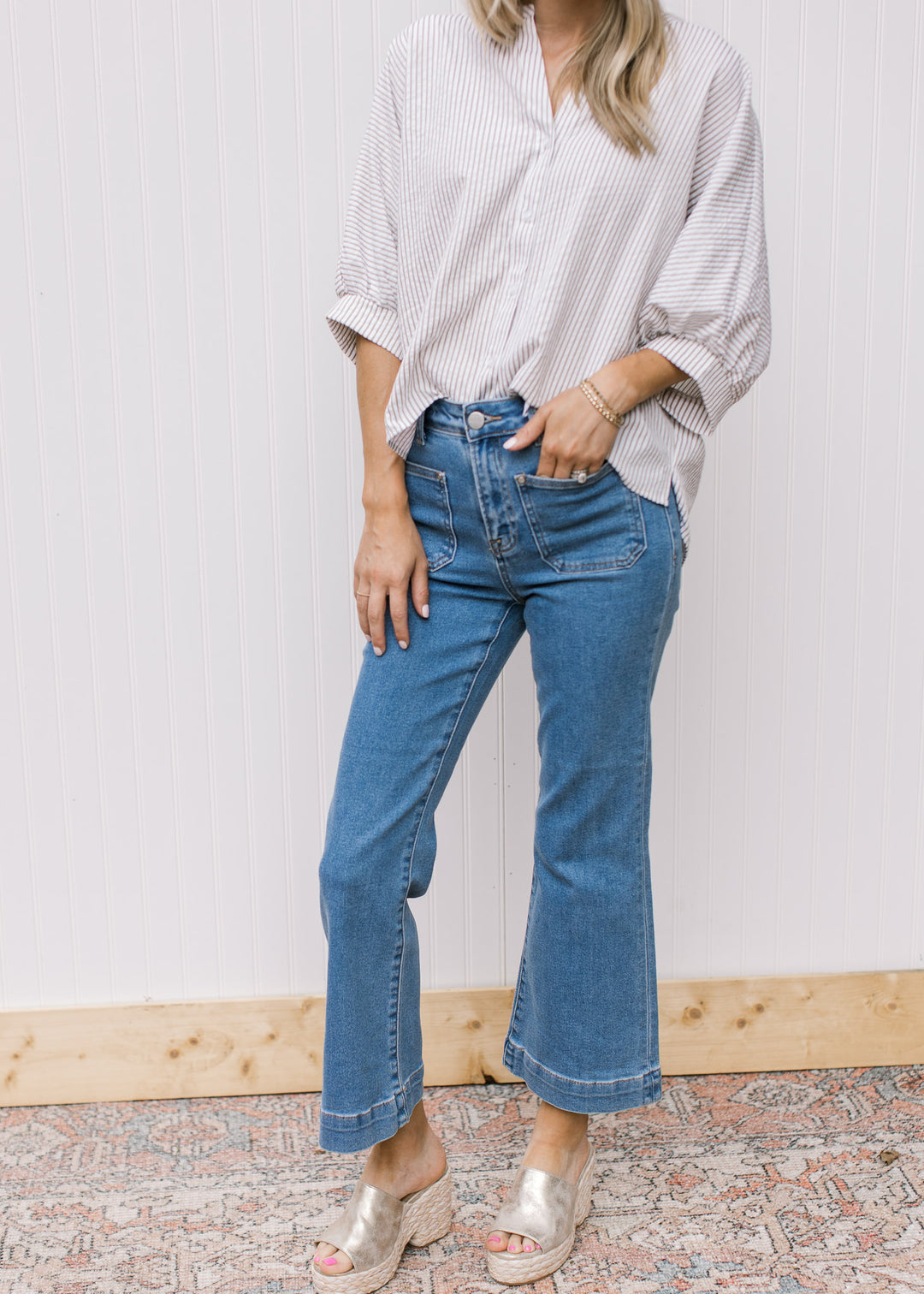 Model wearing medium washed, high rise jeans with front patch pockets and ankle boot cut.