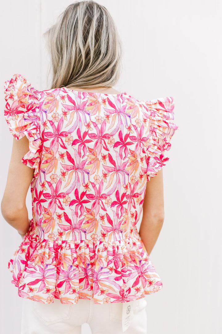 Back view of Model wearing a bold floral v-neck top with ruffle short sleeves and pleating detail.