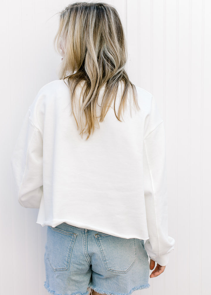 Back view of Model wearing a slightly cropped white sweatshirt with a fabric USA patch.