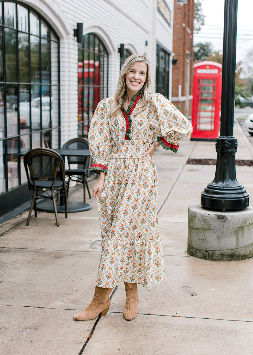 Model wearing a cream maxi with warm floral and a rust and hunter green detail at v-neck and cuffs.