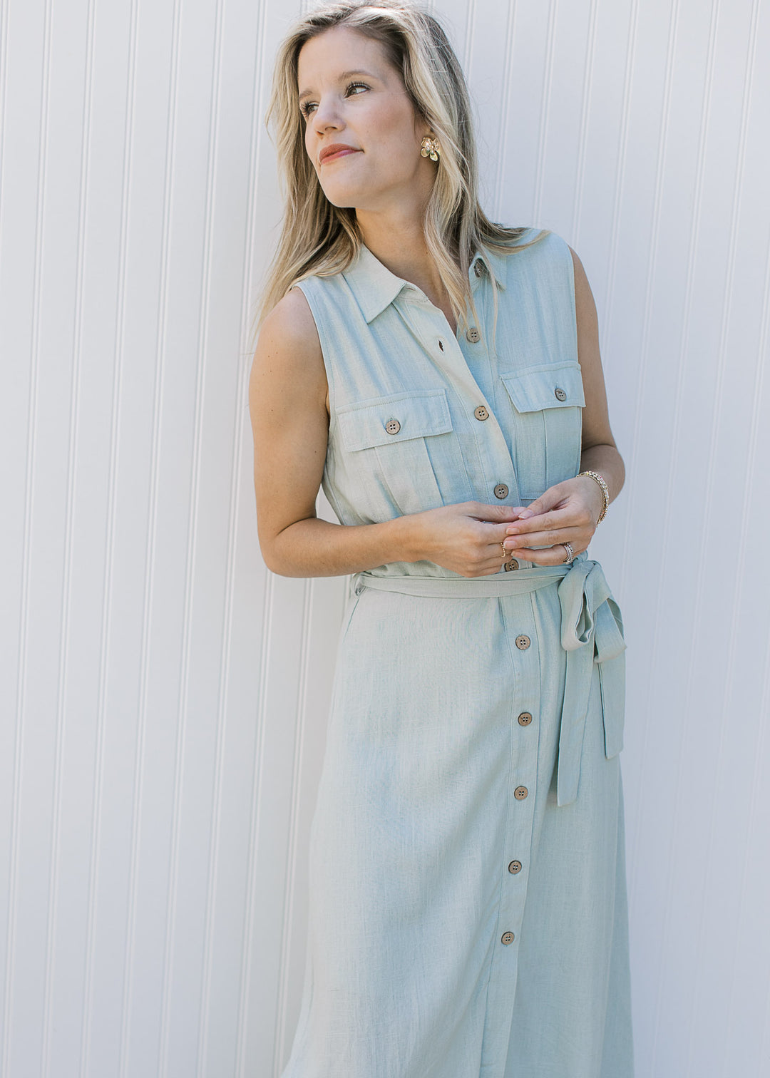 Model wearing a sleeveless, soft basil maxi with button front and patch front pockets.