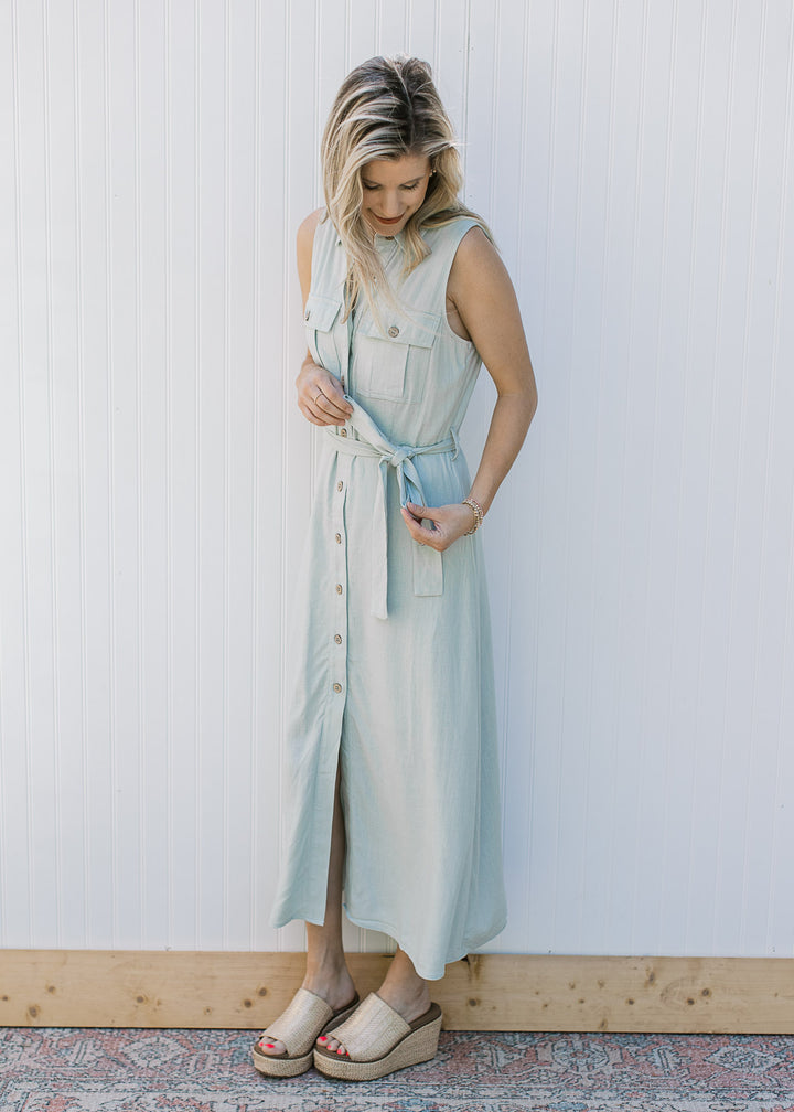 Model wearing wedges and a sleeveless, soft basil maxi with button front and a tie at the waist.
