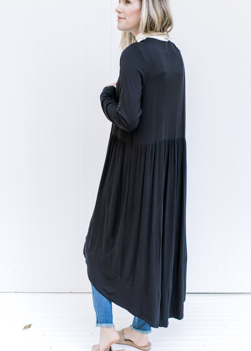 Side view of Model wearing a black long sleeve cardigan with a duster length and an open front.