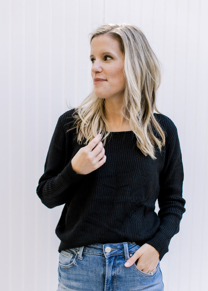 Model wearing a lightweight black ribbed top with long sleeves and a round neckline.