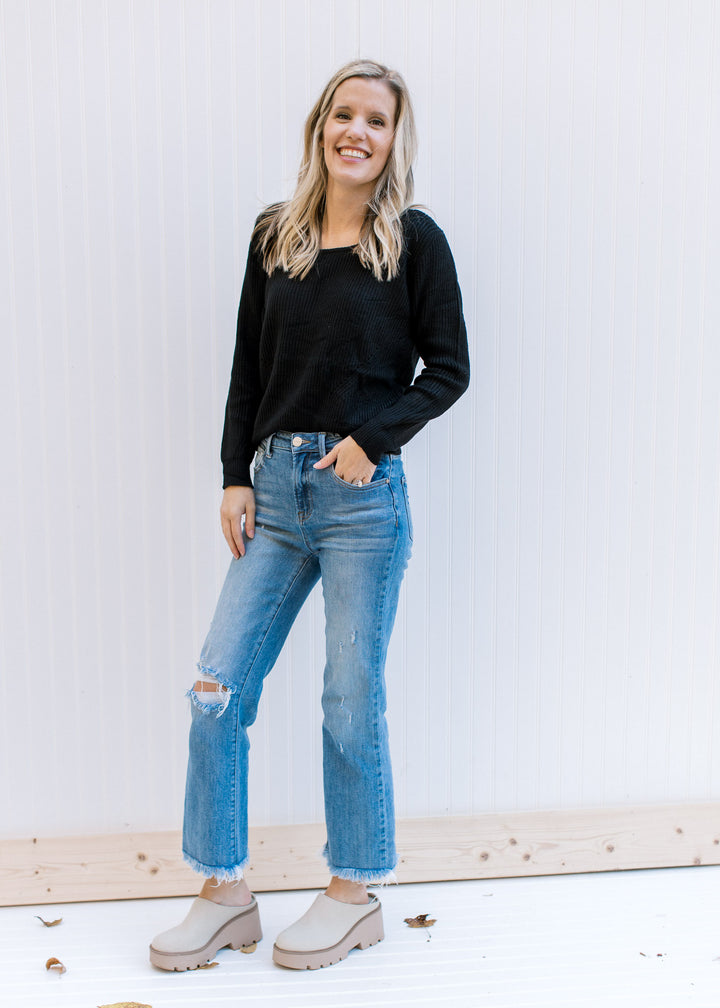 Model wearing jeans and a lightweight black ribbed top with long sleeves and a round neckline.