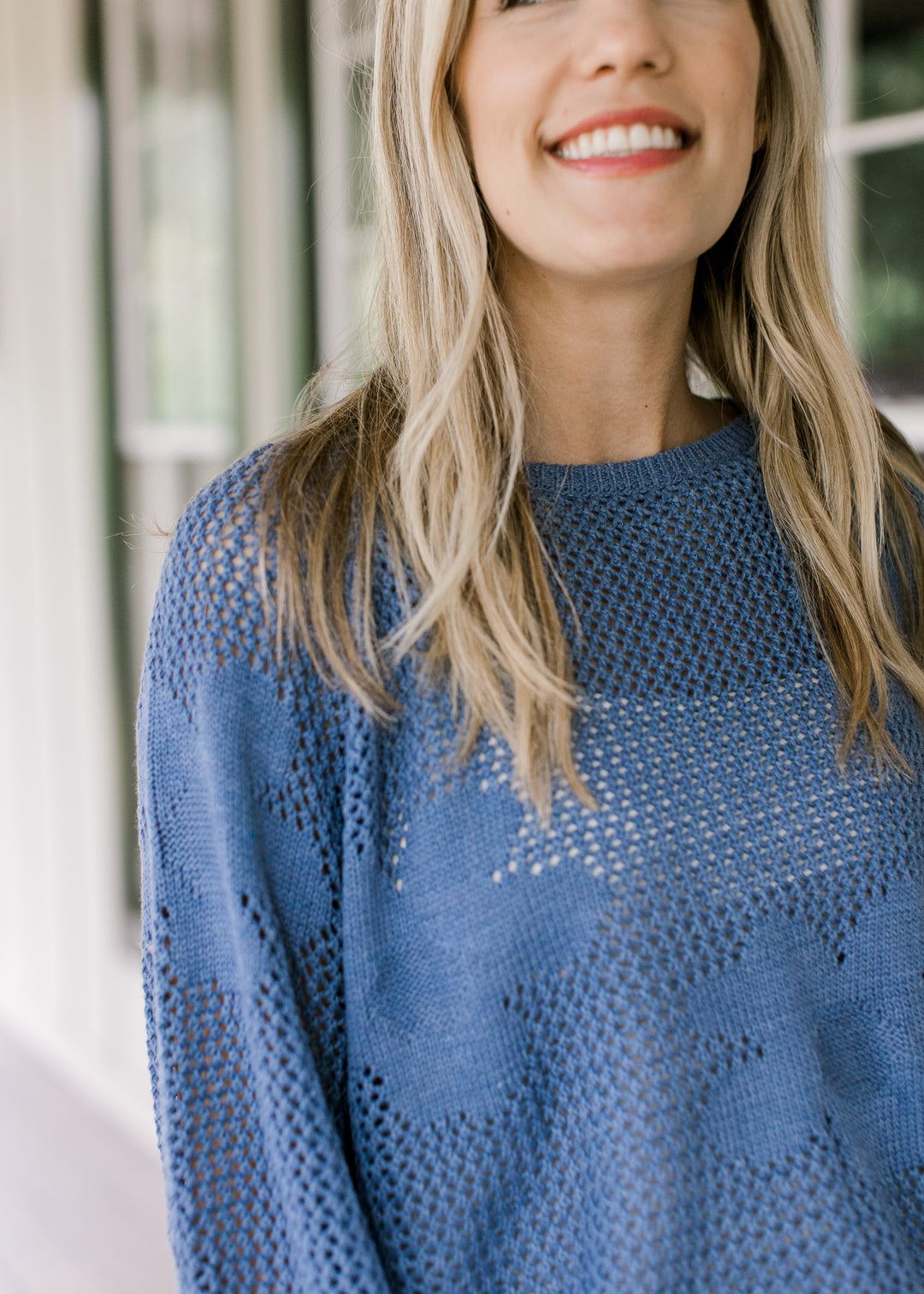 Close up of stitched flowers on a blue open weave sweater with bubble long sleeves.