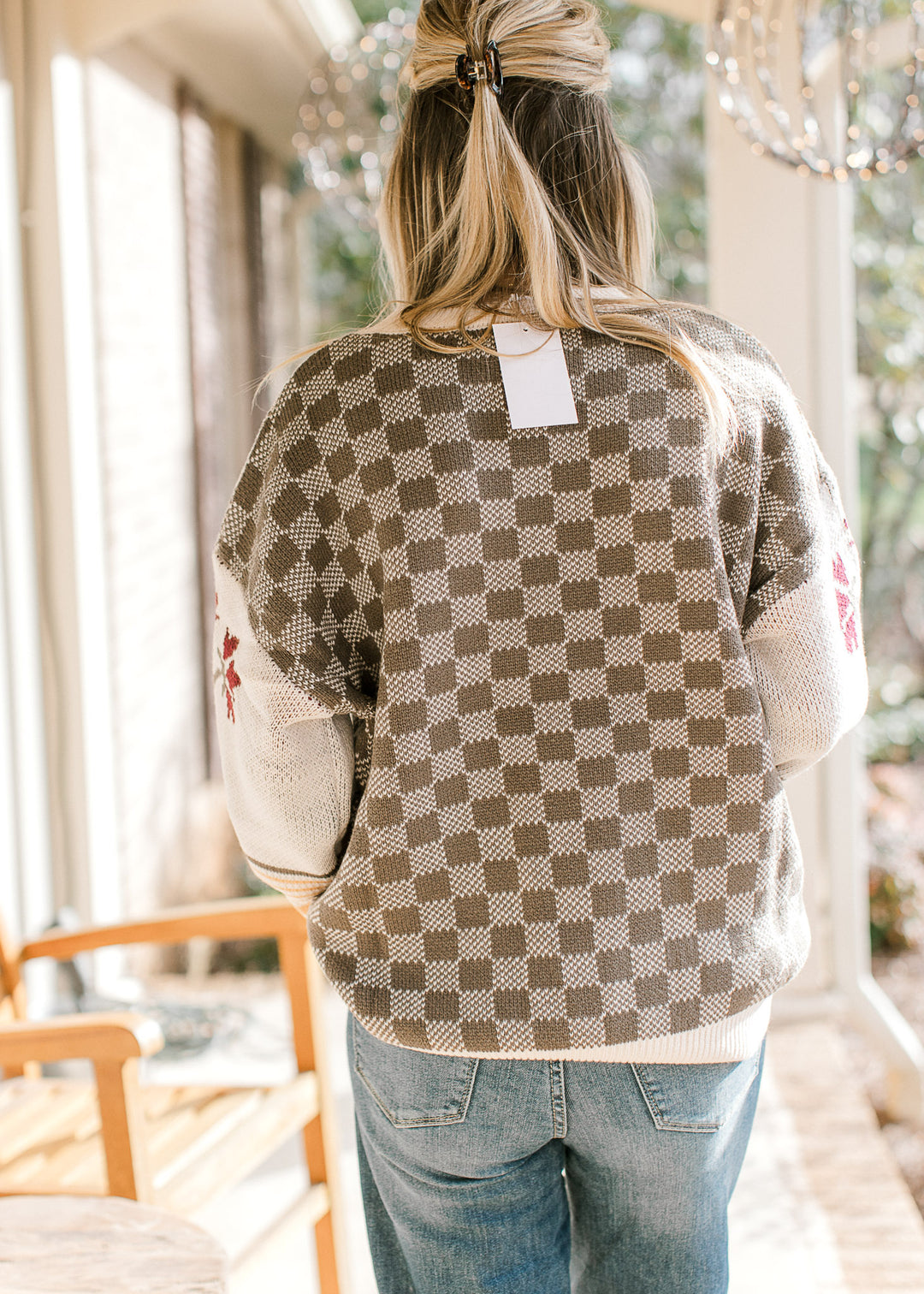 Back view of checked pattern on Model wearing a long sleeve sweater with a round neck.