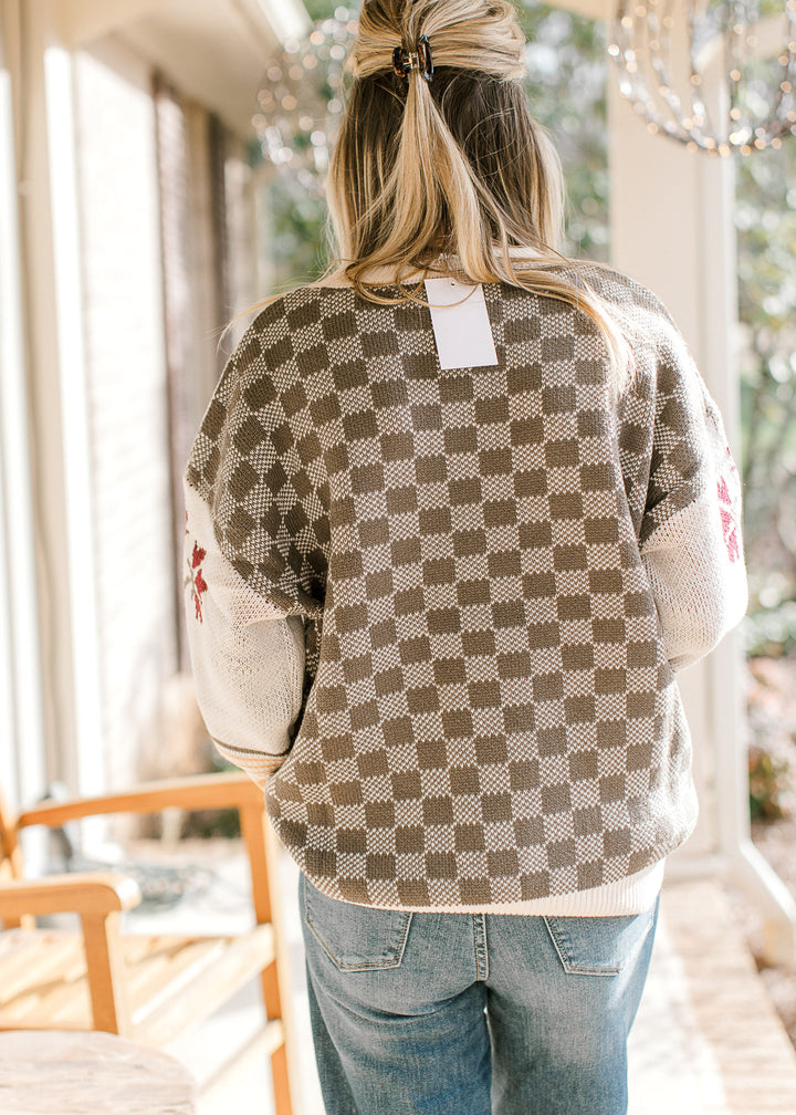 Back view of checked pattern on Model wearing a long sleeve sweater with a round neck.