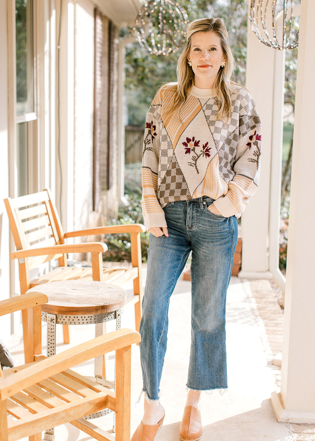 Model wearing jeans and a long sleeve sweater with geometrical botanical print and a round neck.