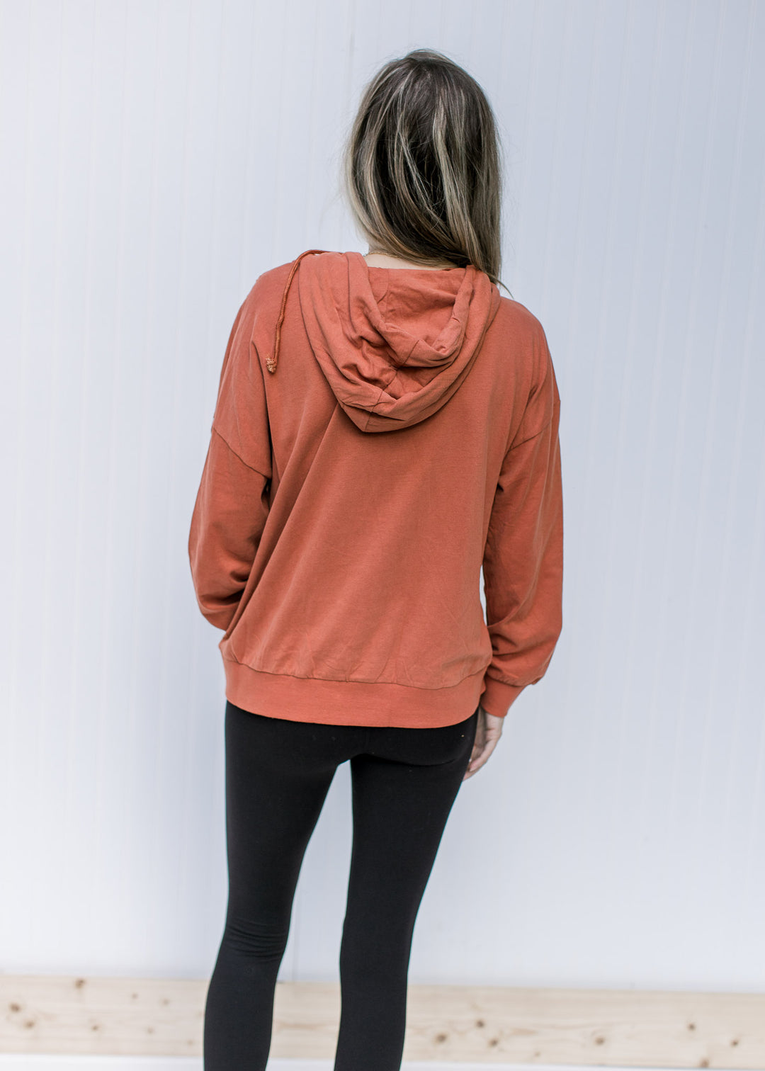 Back view of brick colored long sleeve sweatshirt with an extended shoulder and a hood.
