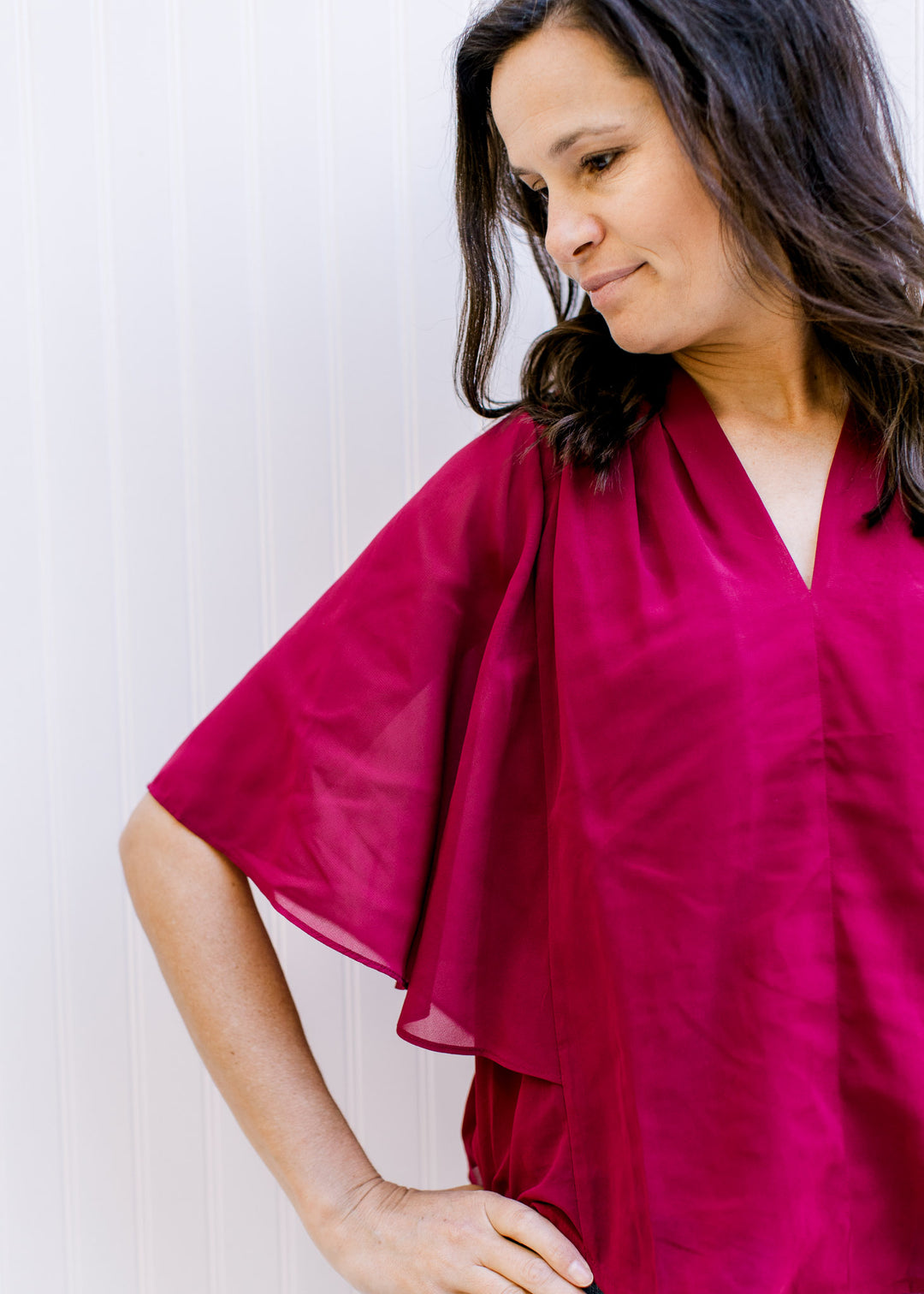 Model wearing a fully lined, burgundy blouse with kimono sleeves and v-neck.