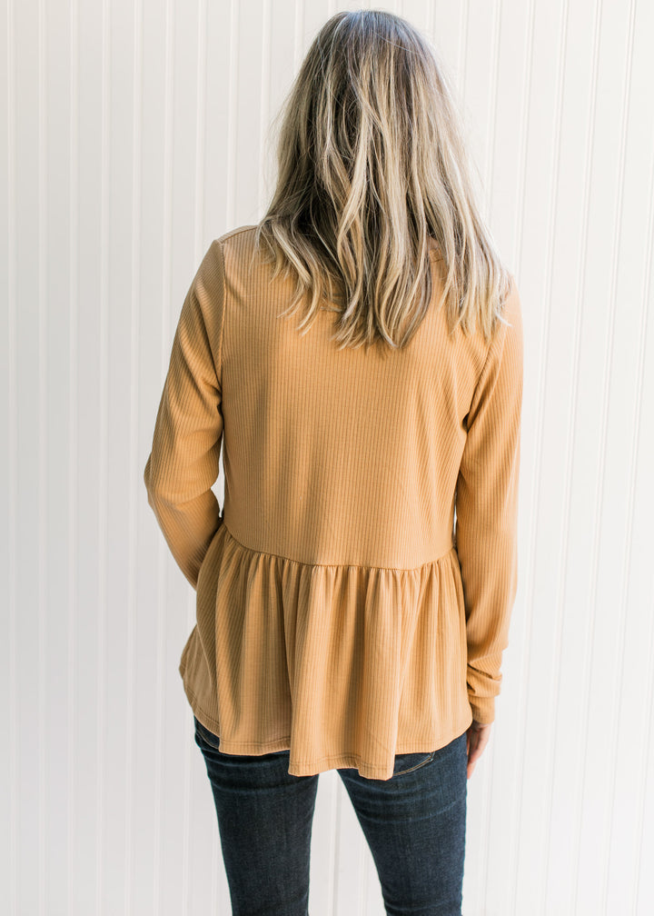 Back view of Model wearing a ribbed butterscotch top with long sleeves, a v-neck and a babydoll fit.