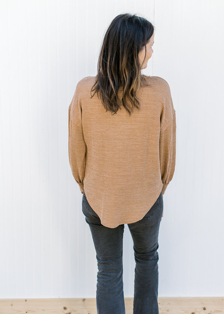 Back view of Model wearing a ribbed camel top with long sleeves and exposed hem.