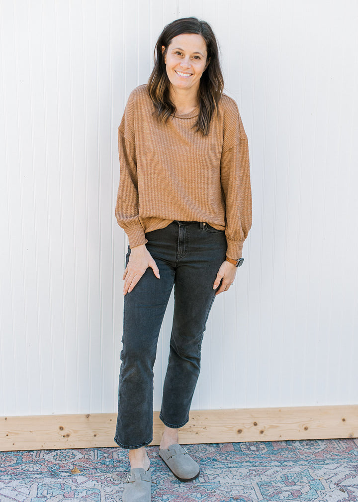 Model wearing black pants, clogs and a ribbed camel top with long sleeves and a round neck.