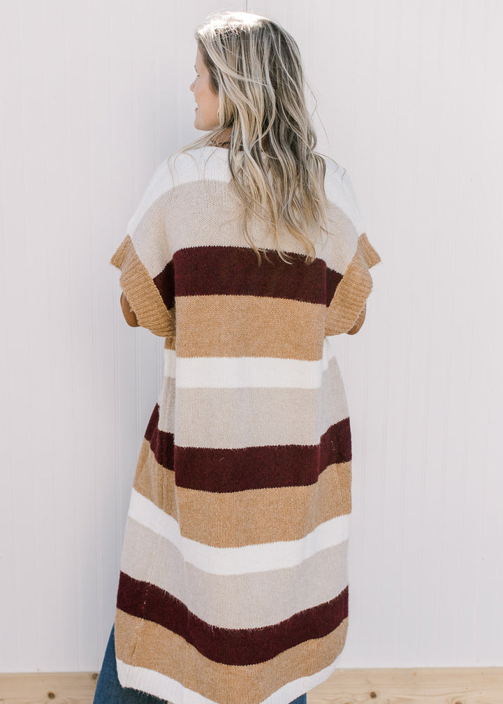 Back view of Model wearing a knit colorblock duster with cream, camel and  maroon stripes.