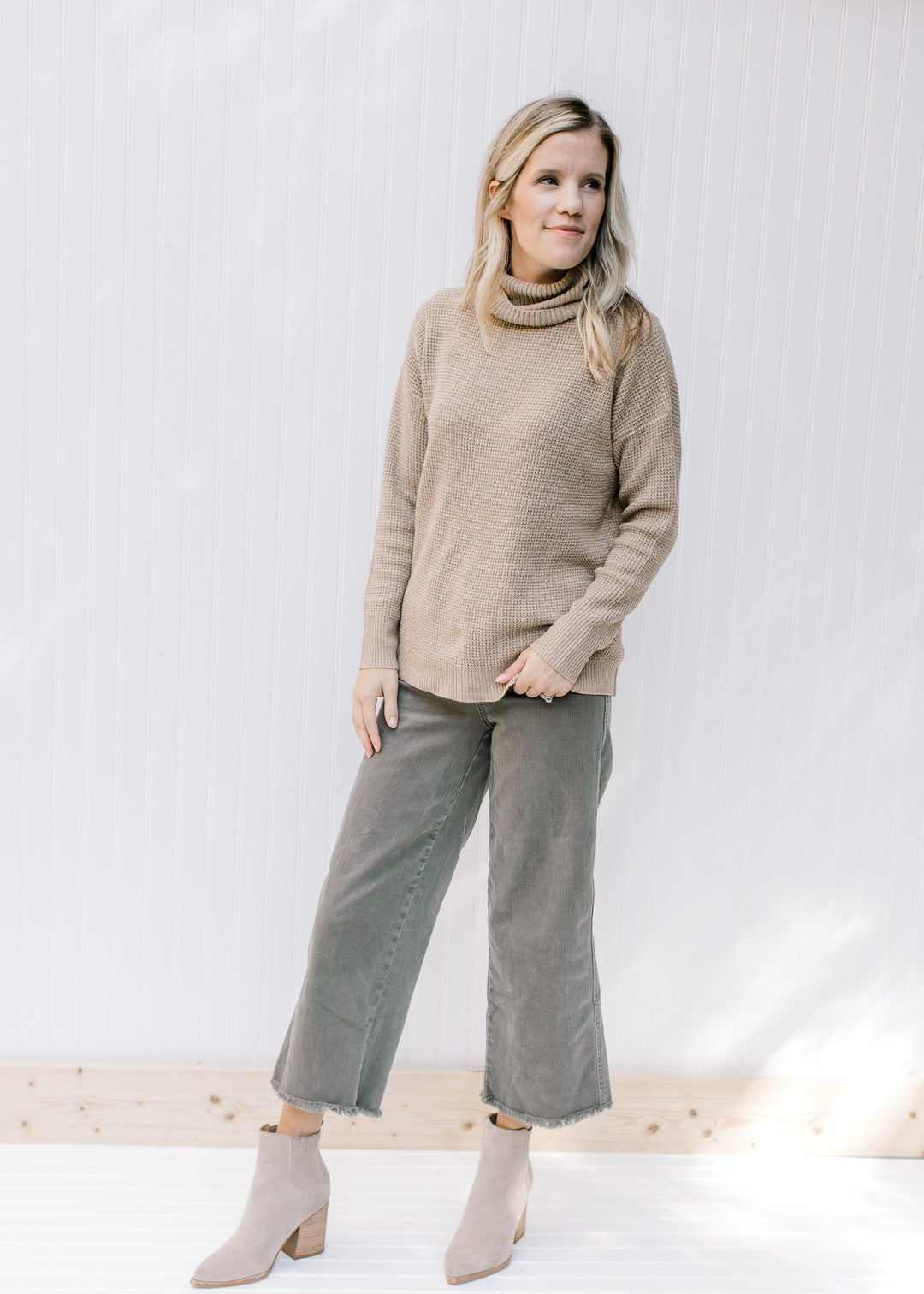 Model wearing wide leg pants, booties and a taupe long sleeve sweater with a honeycomb pattern.