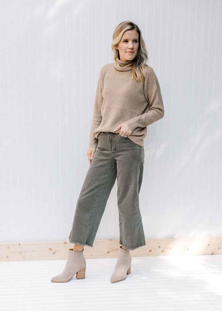 Model wearing wide leg pants with a taupe sweater with a loose turtle neck and long sleeves.