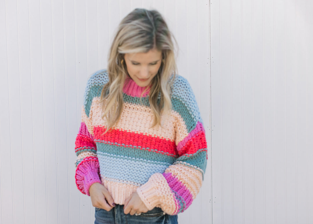 Model wearing a chunky color block knit sweater with long sleeves and a cropped fit.