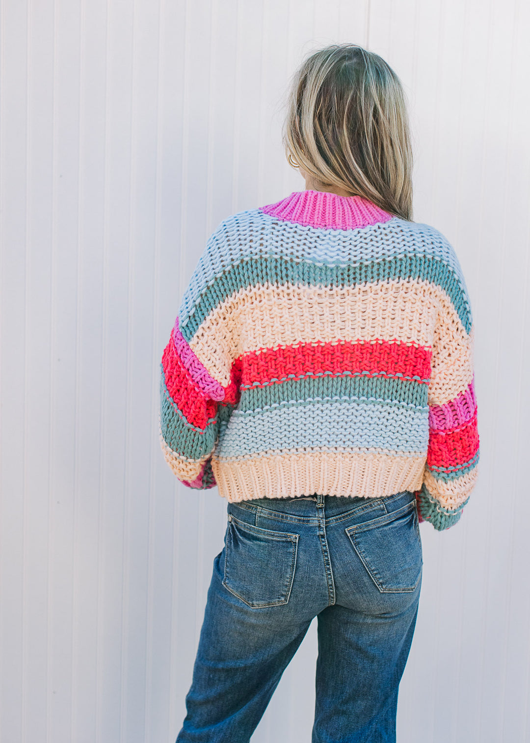 Back view of Model wearing a color block knit sweater with long sleeves and a round neck.
