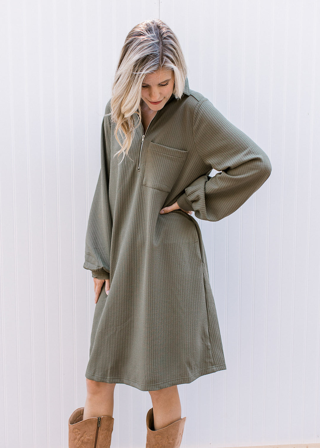 Model wearing an olive ribbed midi with a quarter zip neck, long sleeves and a patch pocket.