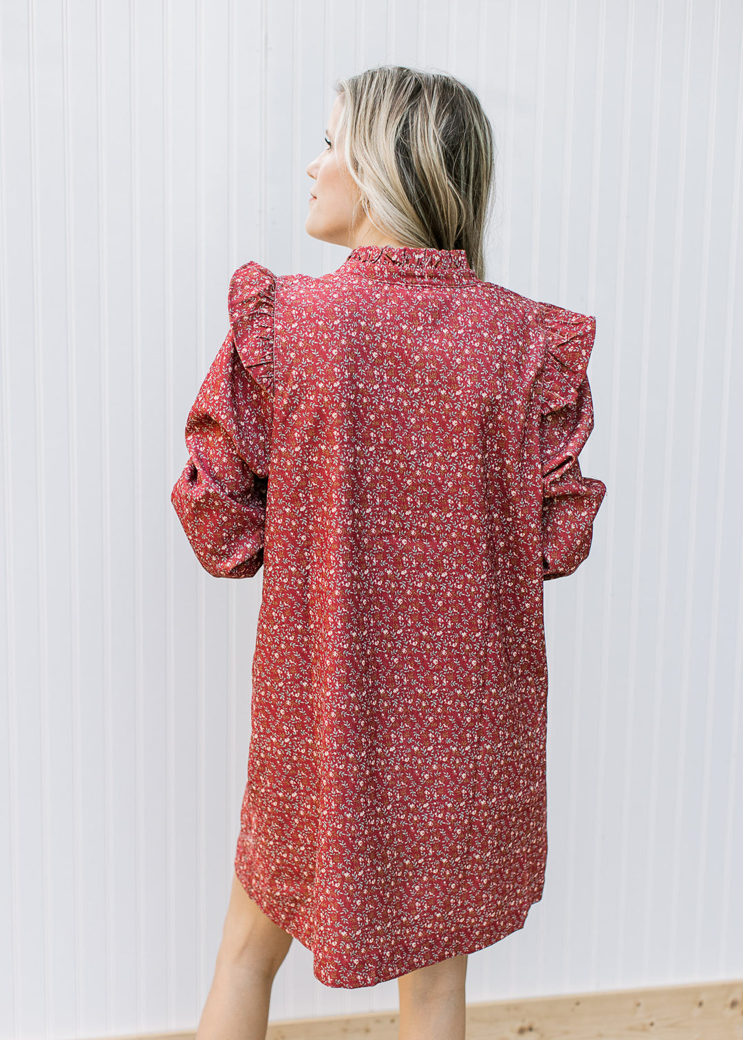 Back view of Model wearing a rust dress with cream ditsy floral and long sleeves.