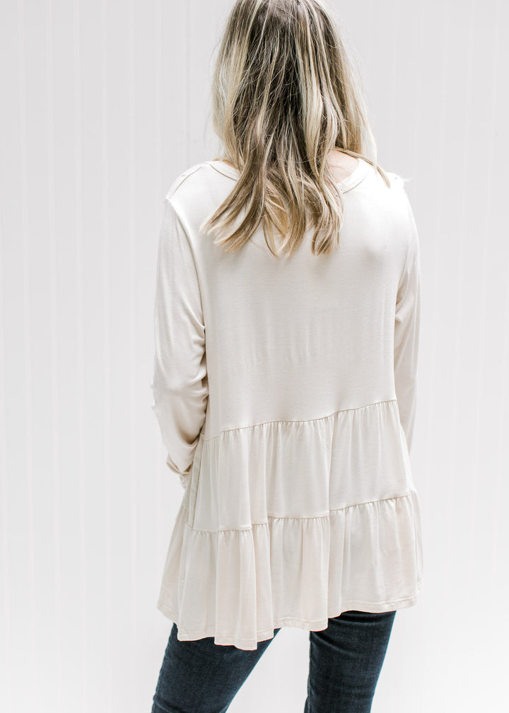 Back view of Model wearing a cream tiered top with long sleeves and composed of bamboo viscose.