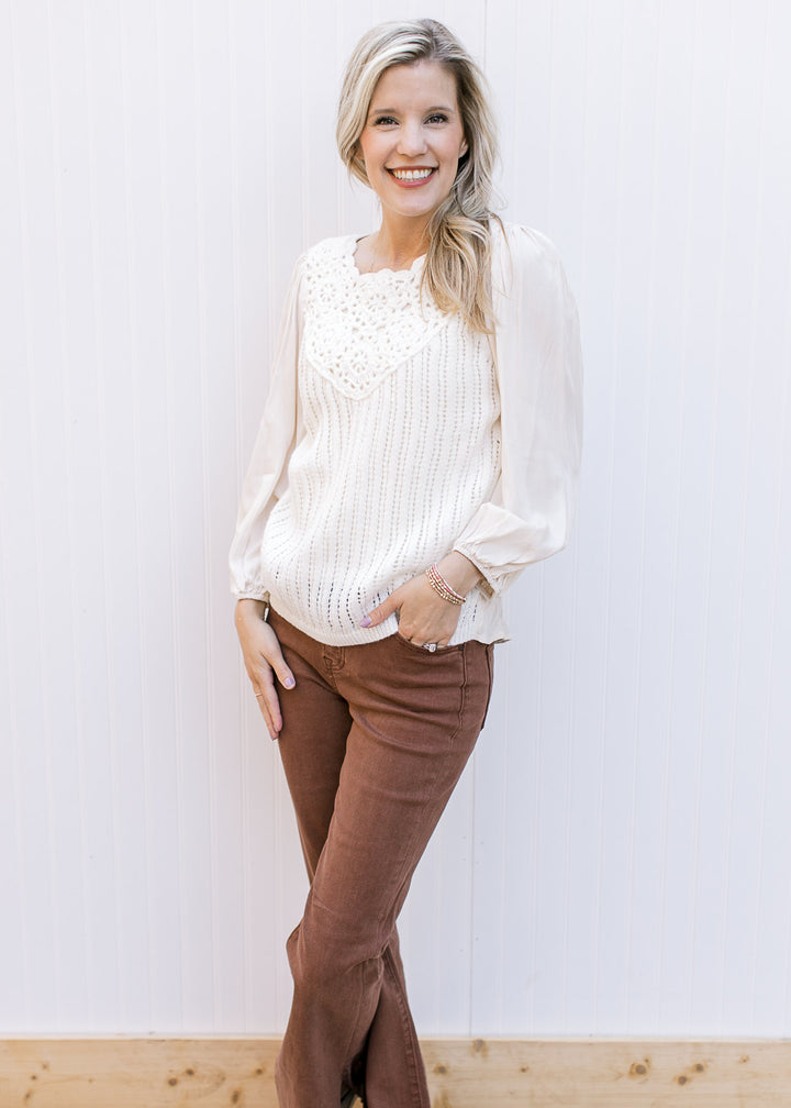 Model wearing a cream top with crochet front, pleated shoulders and 3/4 sleeves.
