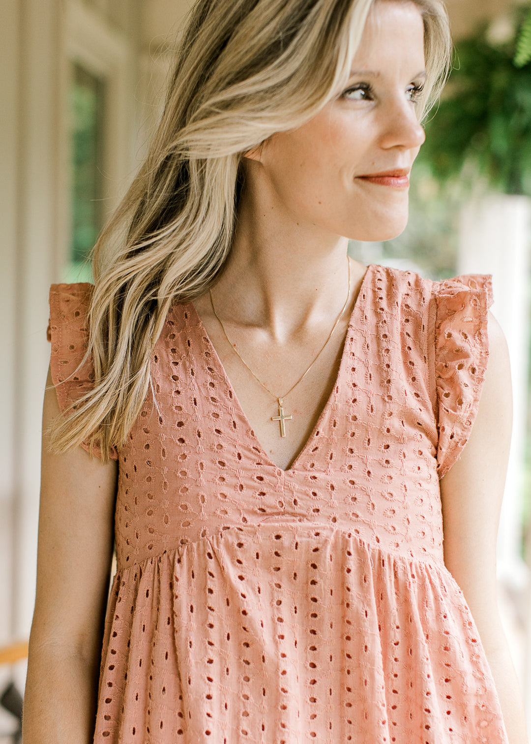 Close up of v-neck, ruffle sleeve and eyelets on a coral midi with full lining and pockets.