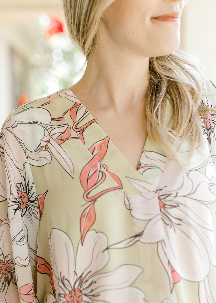 Close up of v-neck on a pale lime top with cream and coral floral and sheer 3/4 sleeves.
