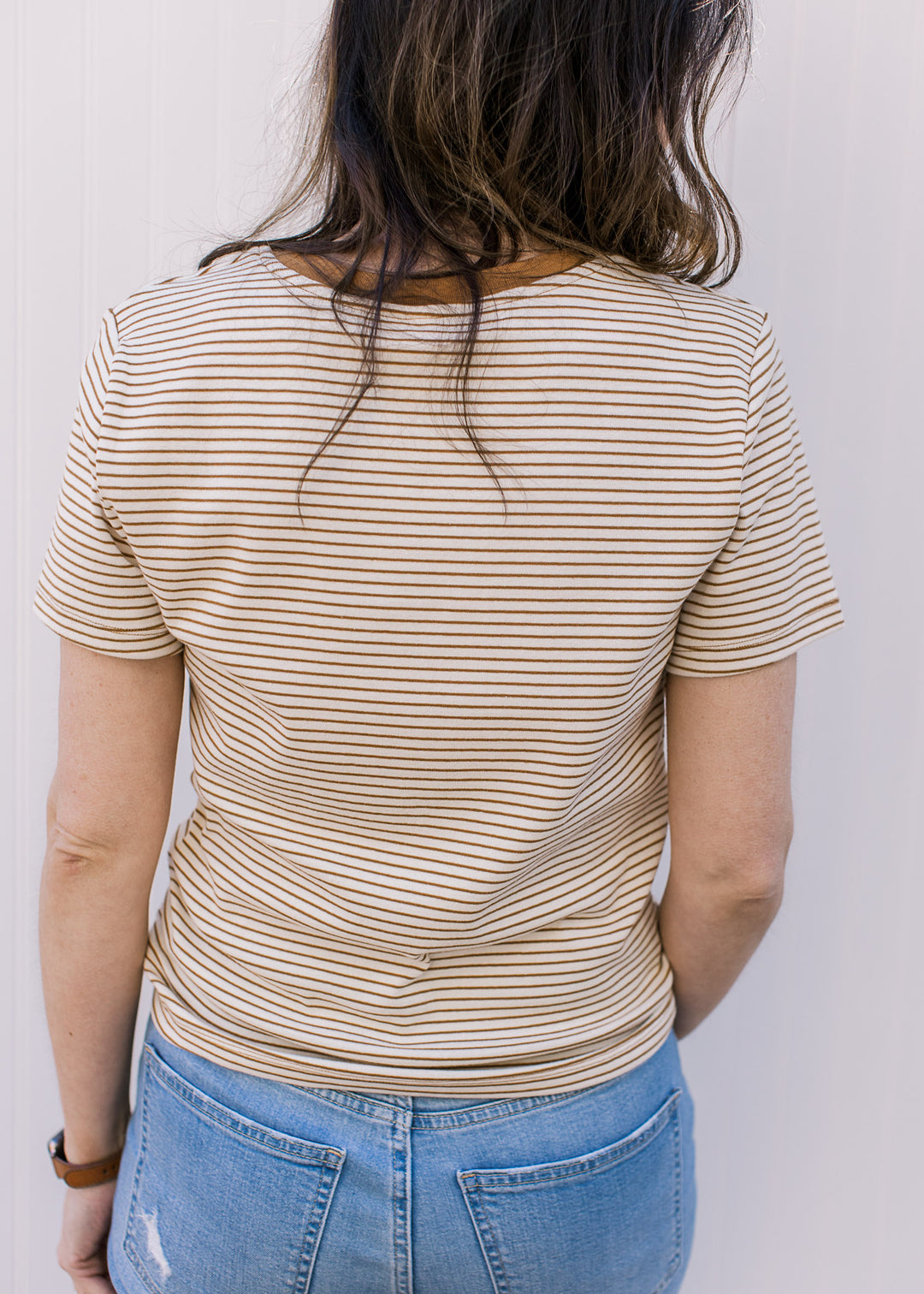 Back view of Model wearing a ecru and camel crew neck tee with stripes and short sleeves.