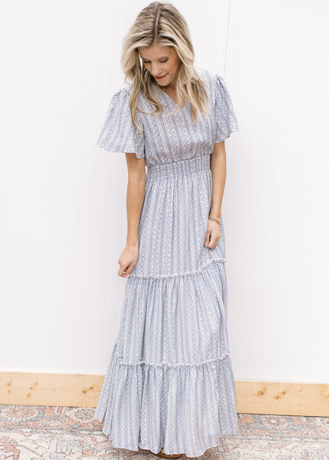 Model wearing a V-neck white maxi with a pale blue print, short sleeves and a wide elastic waist.