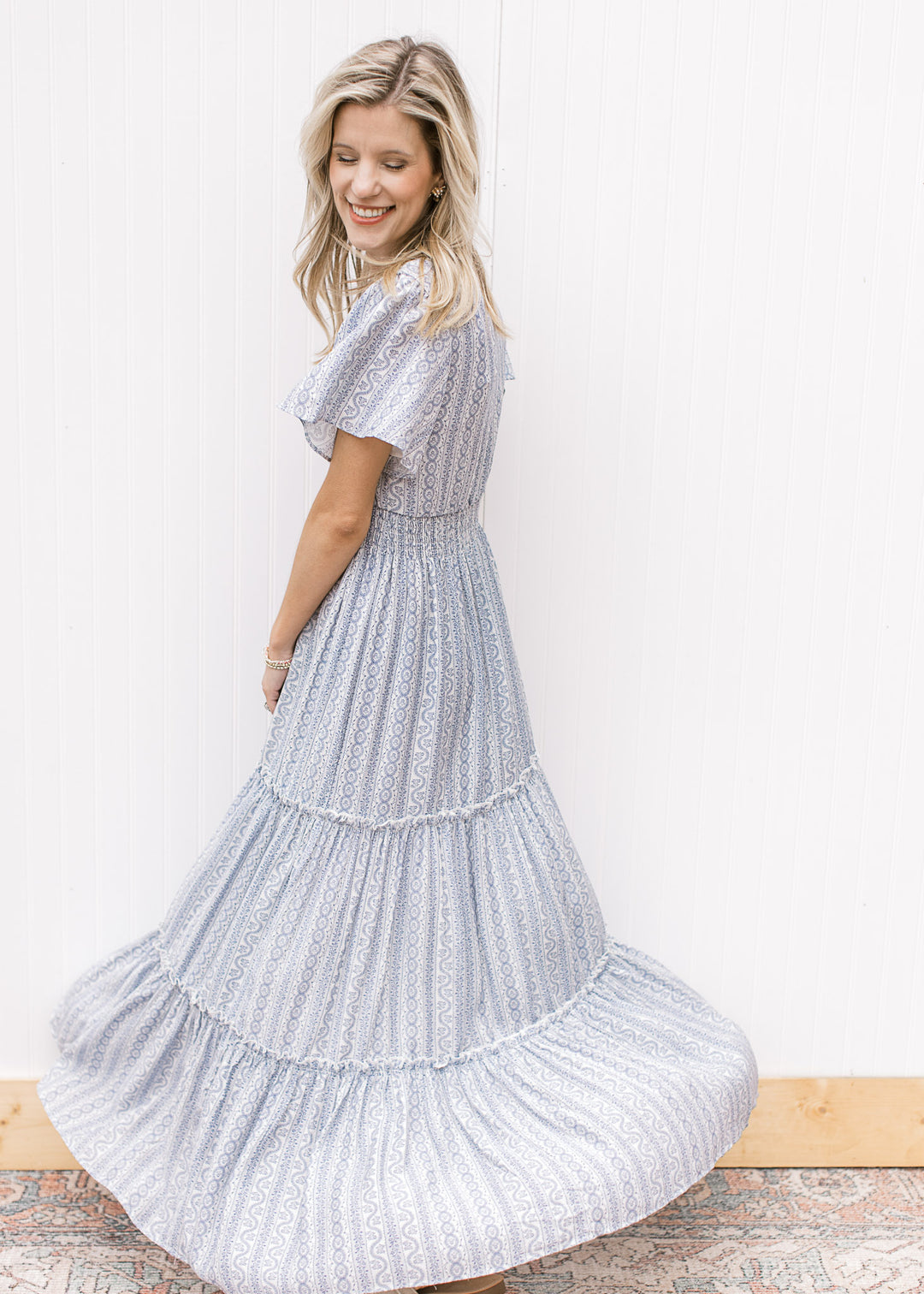 Model spinning in a V-neck white maxi with a pale blue print, short sleeves and an elastic waist.