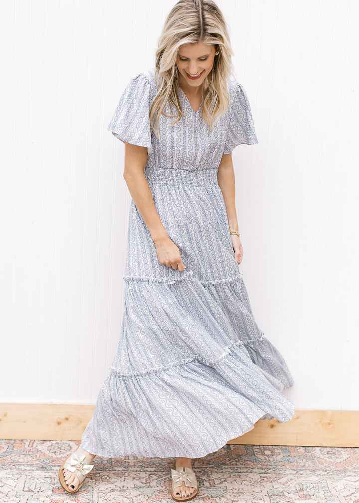 Model wearing a V-neck white maxi with a pale blue print, short sleeves and a wide elastic waist.