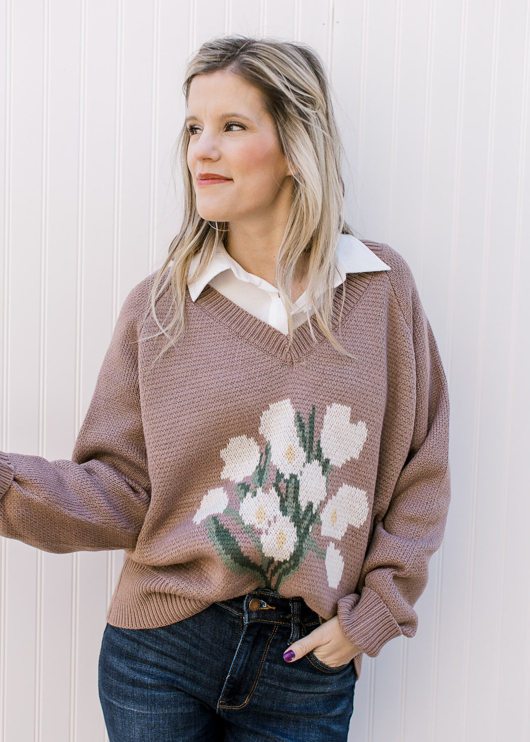 Model wearing a lavender v-neck sweater with white floral bouquet on the front and long sleeves.