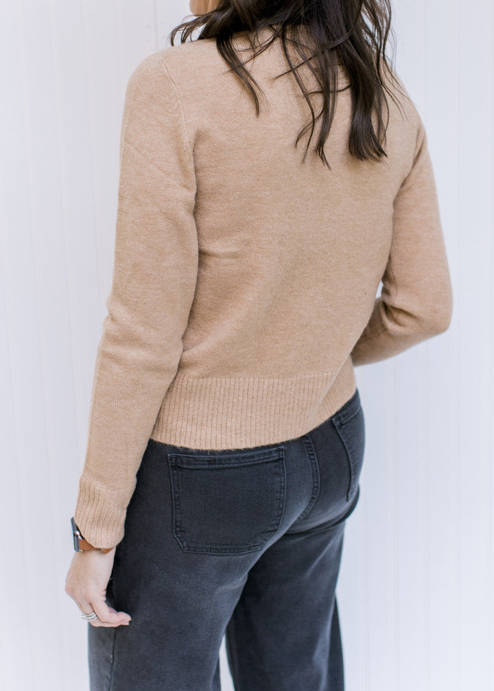Back view of Model wearing a classic camel colored top with a mocked neckline and long sleeves.