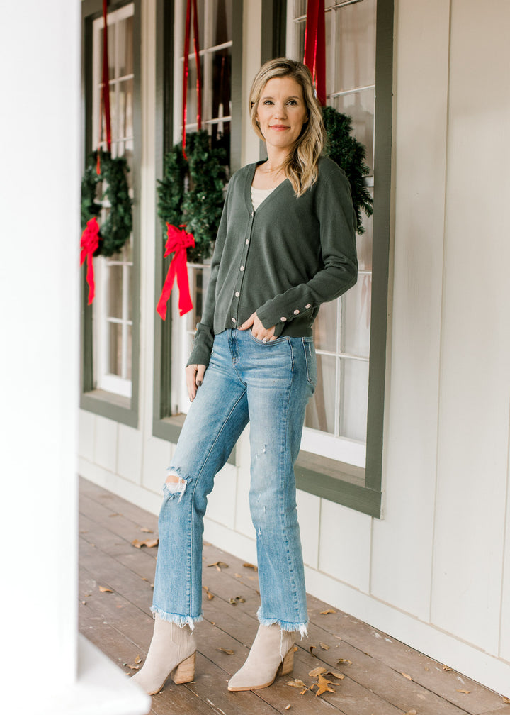 Model wearing jeans and booties with a green long sleeve cardigan with button closure.