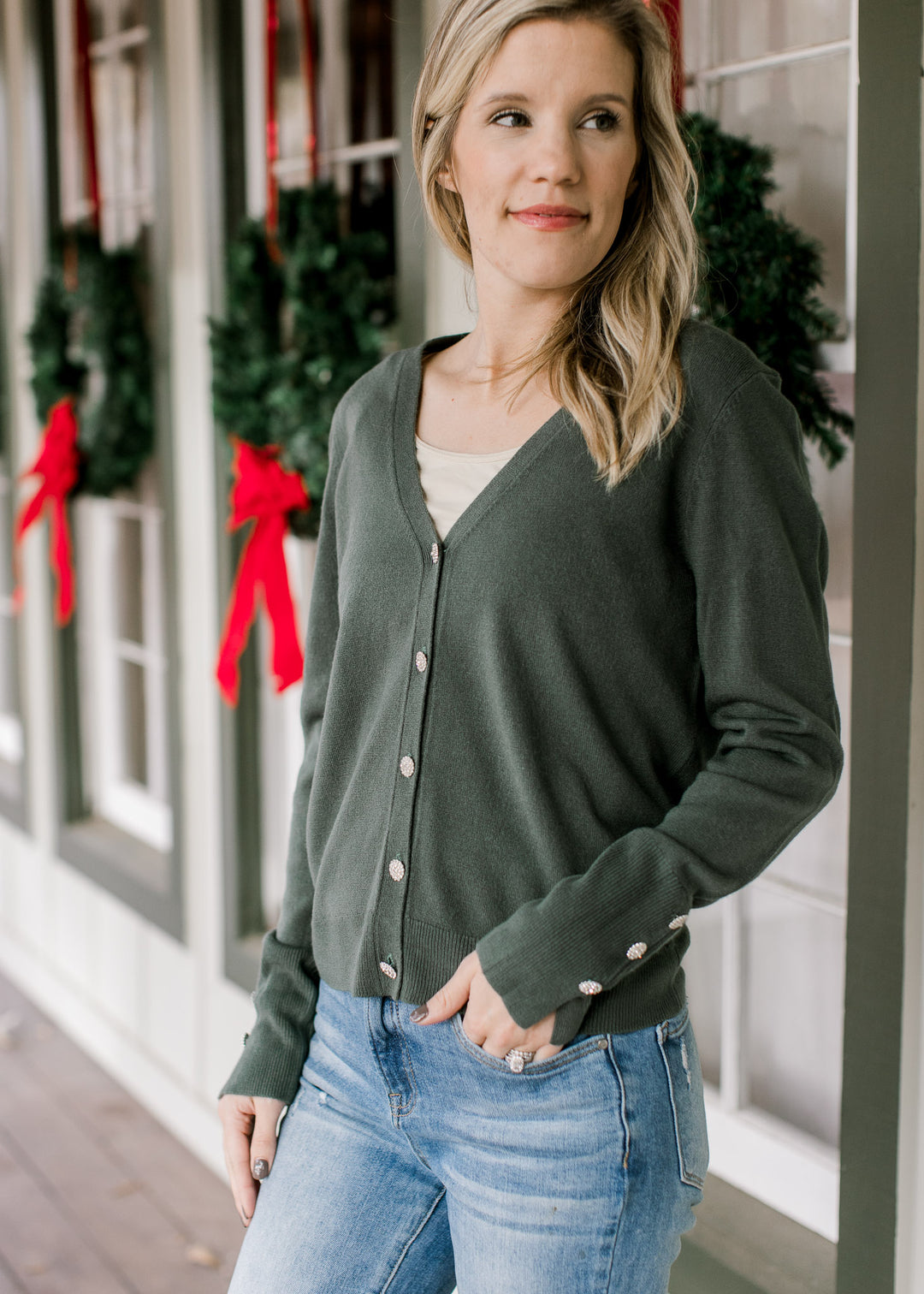 Model wearing a green long sleeve cardigan with flower rhinestone button closure and cuff detail.