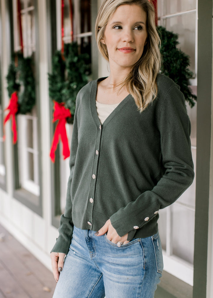 Model wearing a green long sleeve cardigan with flower rhinestone button closure and cuff detail.