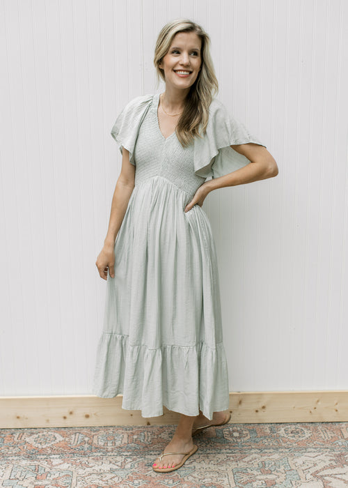 Model wearing a pale green maxi with a smocked bodice, flutter short sleeves and a v-neck.
