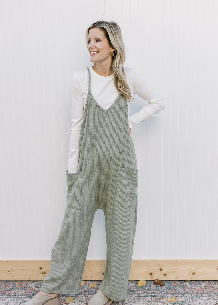 Model wearing a green jumpsuit over a cream long sleeve body suit with a crew neckline.