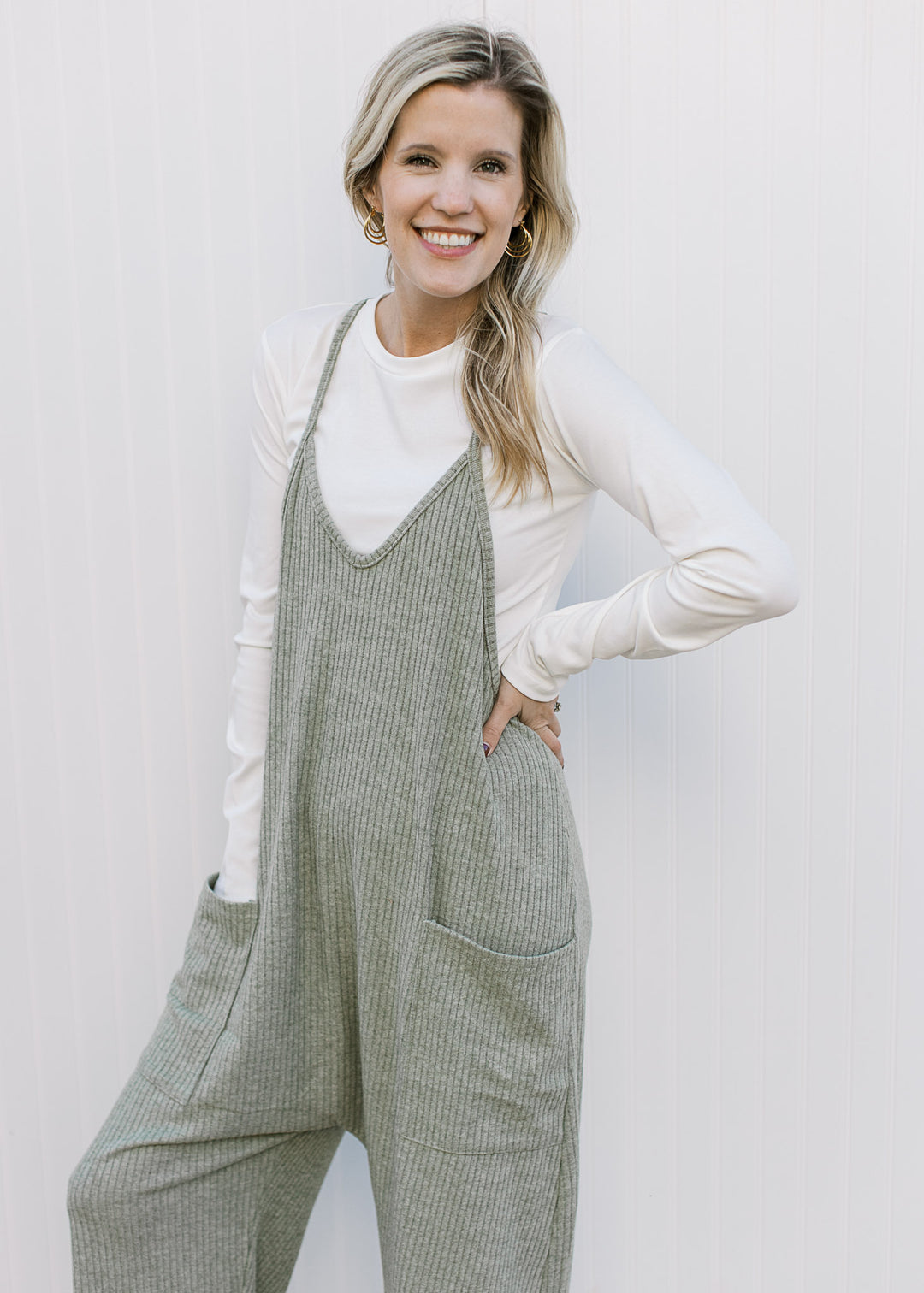 Model wearing a white top with a moss green jumper with front patch pockets and wide legs.