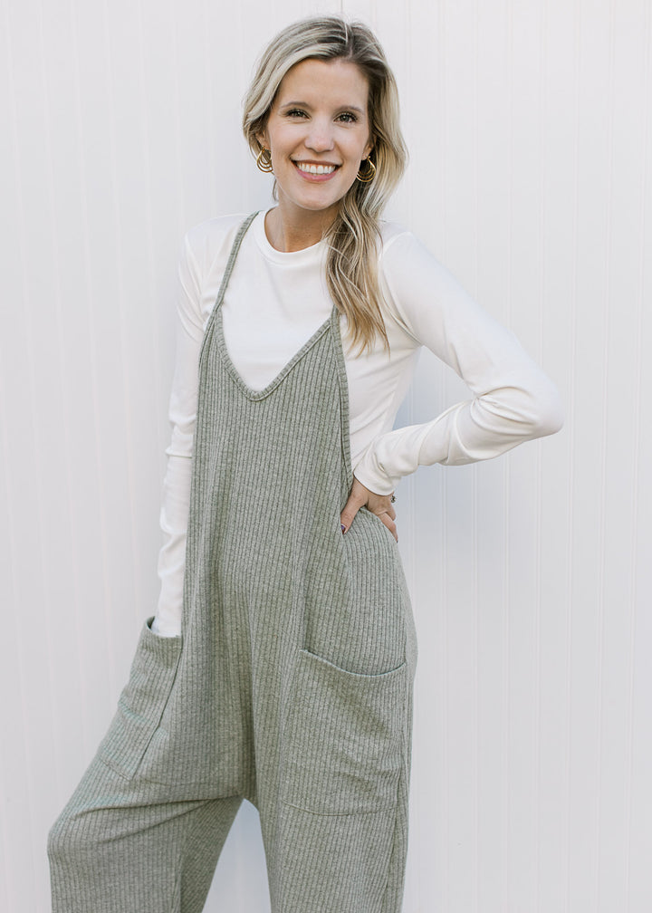 Model wearing a white top with a moss green jumper with front patch pockets and wide legs.