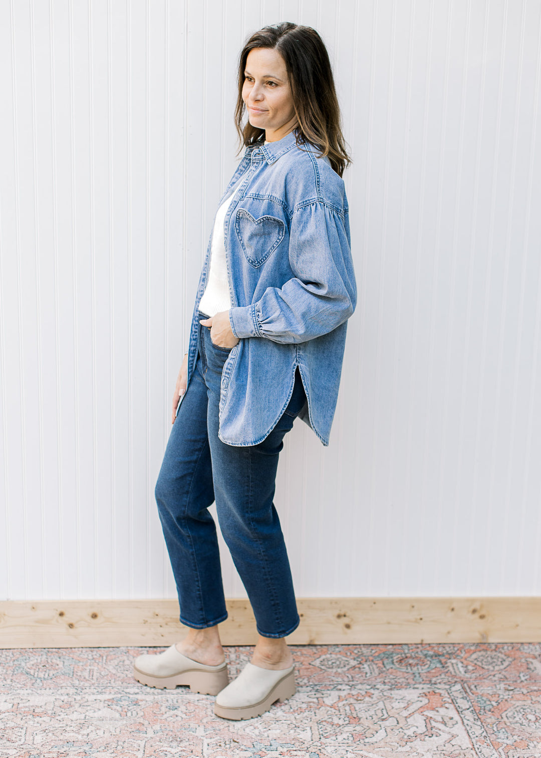Model wearing an oversized chambray button down with long sleeves and a detail heart pocket.