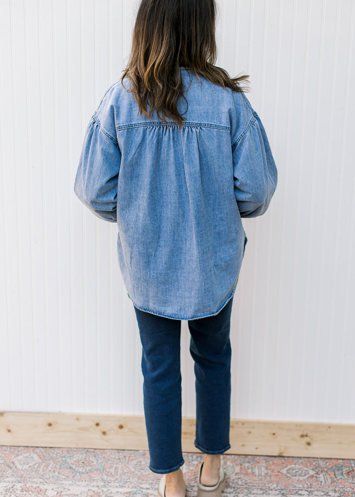 Back view of Model wearing an oversized chambray button down with long sleeves.