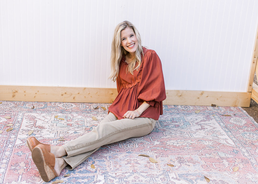 Model wearing a rust top with high rise khakis with side hem detail and cropped cut.