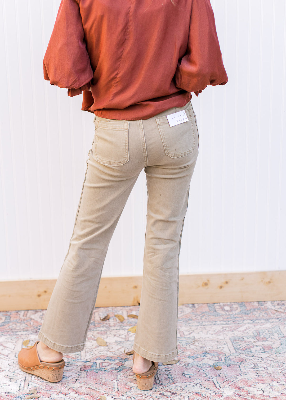 Back view of Model wearing high rise straight leg khakis with side hem detail and cropped cut.