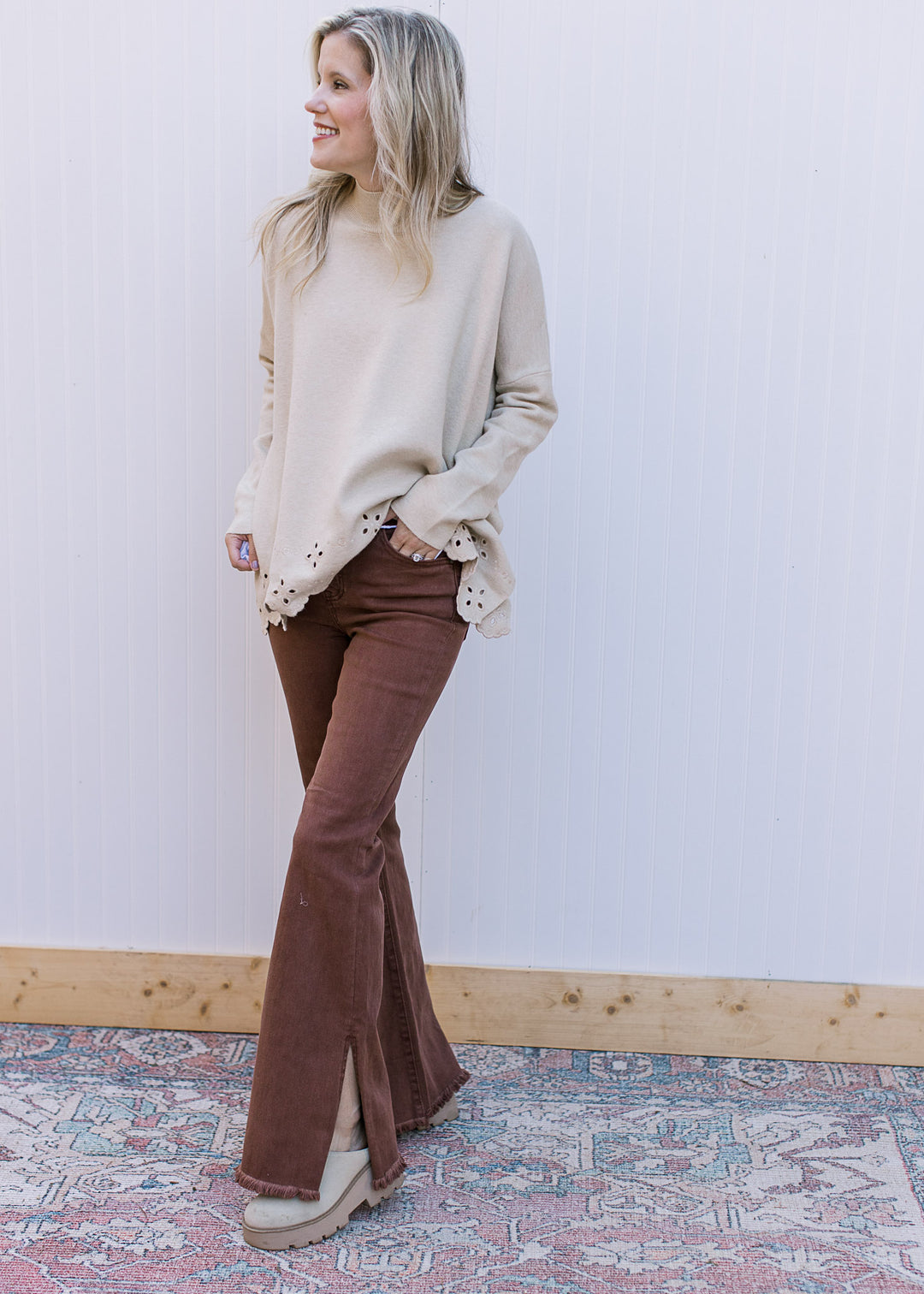 Model wearing a cream top and espresso colored jeans with raw hem and a flare leg.