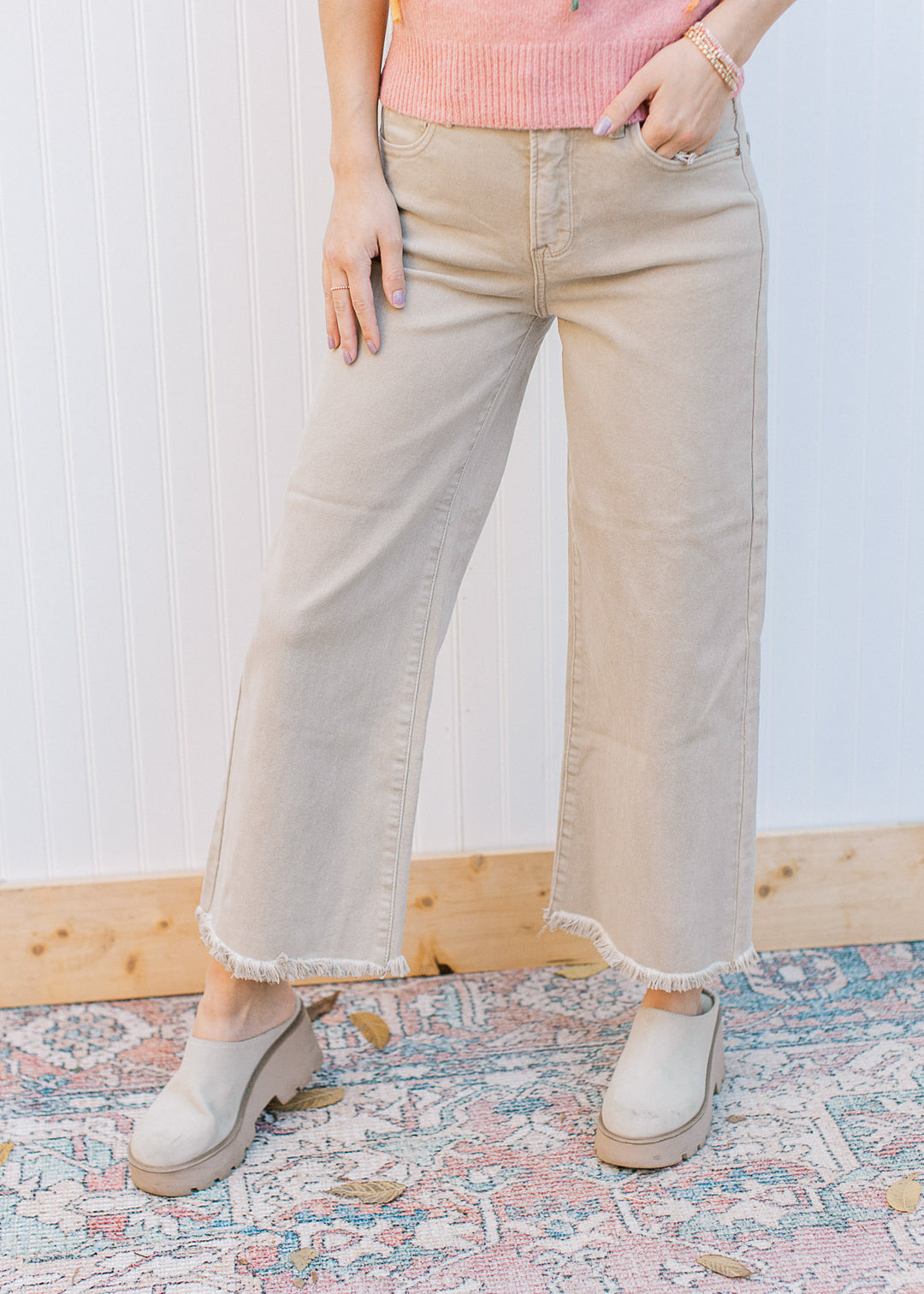 Model wearing mules with khaki high rise jeans with a cropped fit, frayed hem and wide legs.